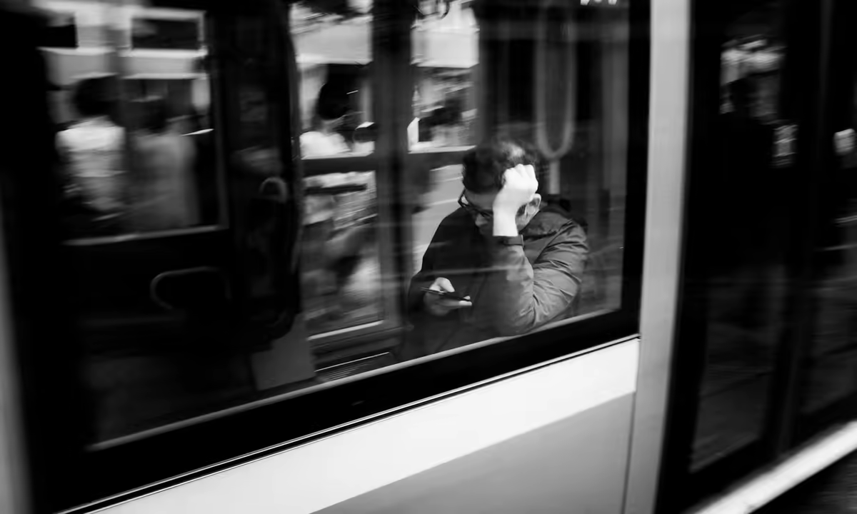 a passenger uses a smartphone behind the window of moving public transport